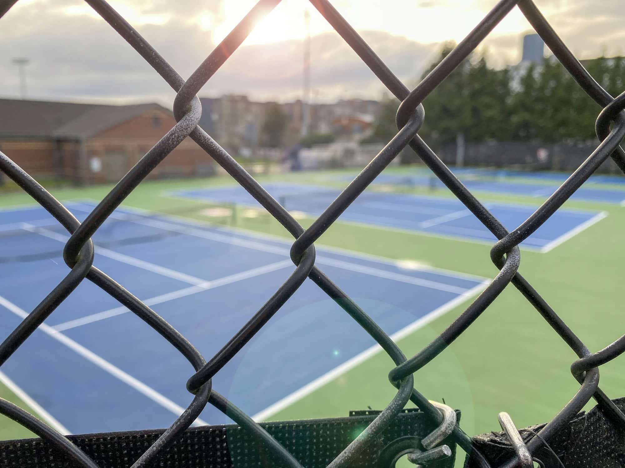 Leere Tennisplätze, die durch einen Maschendrahtzaun betrachtet werden