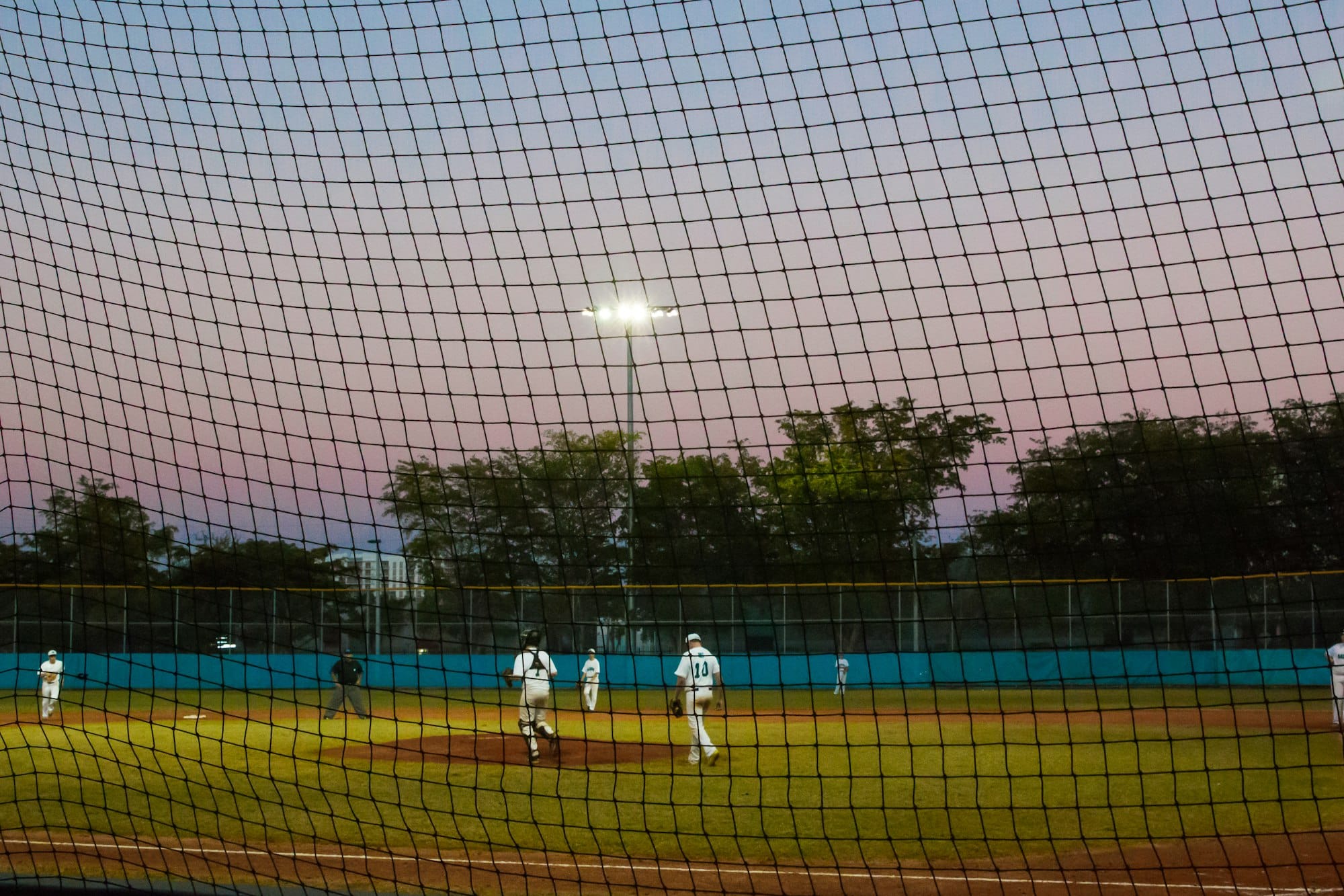 Pôr do sol sobre crianças do ensino médio em um campo de beisebol jogando